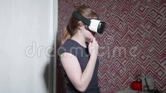 穿着巴尔克T恤的戴VR眼镜的白人女孩既害怕又担心女孩害怕现实视频的预览图