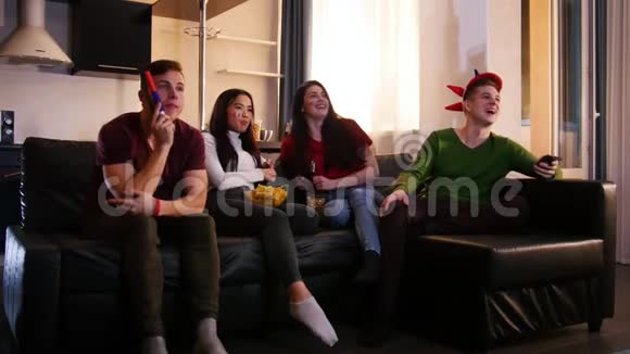 四个快乐的年轻人坐在沙发上看足球比赛令人兴奋的年轻人视频的预览图