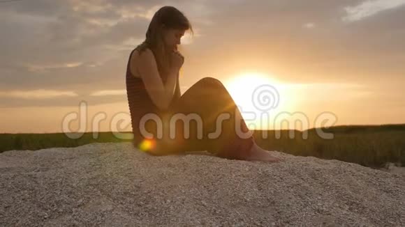 日落时分一位年轻女子在沙滩上的剪影女孩在地平线上向上帝祈祷度假的概念宗教Bea视频的预览图