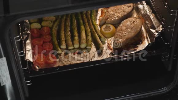 烤鱼牛排和烤箱里的蔬菜女人煮了美味的鲑鱼在家庭厨房准备蔬菜健康饮食视频的预览图