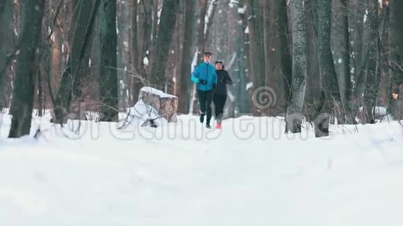 穿运动服装的男女青年在冬林慢跑视频的预览图