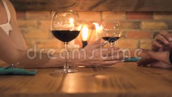 男人和女人牵着手在晚上的餐厅里用蜡烛为两人浪漫晚餐女性和男性视频的预览图