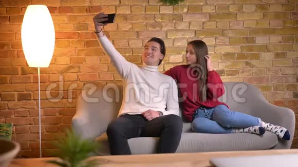 白种人朋友用智能手机制作自拍照片和在家庭氛围中选择最好的照片的肖像视频的预览图