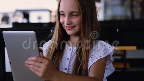 戴耳机的迷人女孩坐在地板上用触摸板和微笑视频的预览图
