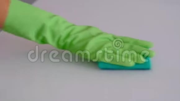 慢动作用绿色橡胶手套把一只家庭主妇的手合起来用清洁剂擦拭桌子上的污垢视频的预览图