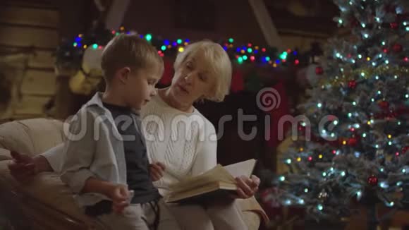 一位老妇人在圣诞夜为一个小男孩读了一本书和他说话视频的预览图