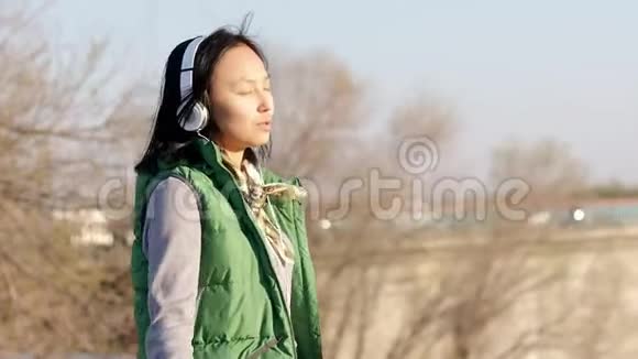 带着耳机听音乐的亚裔混血黑发少女视频的预览图