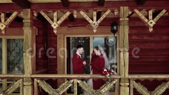 新郎和新娘在村里的木木木屋的阳台上喝咖啡而无人机摄像机则飞走了视频的预览图