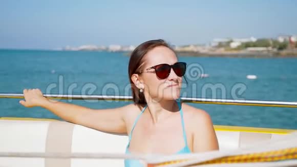 戴墨镜的旅游妇女坐在沿海的摩托艇上视频的预览图