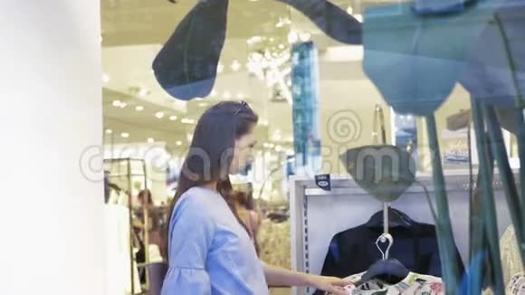 年轻开朗的女人在时尚商场购物选择新衣服视频的预览图