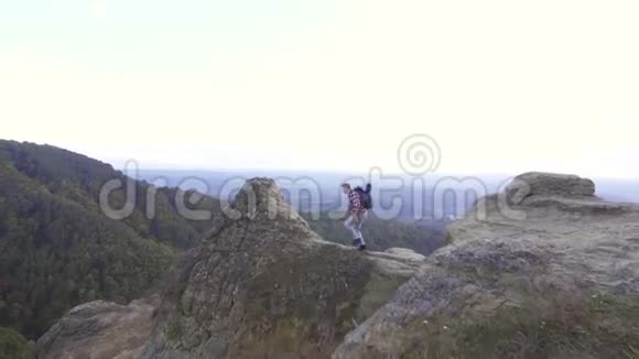 年轻的游客背着背包爬山高兴地举起双手站在山顶视频的预览图