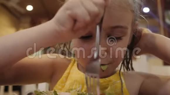 小女孩在餐馆里吃有食欲的绿色沙拉良好的健康观念视频的预览图