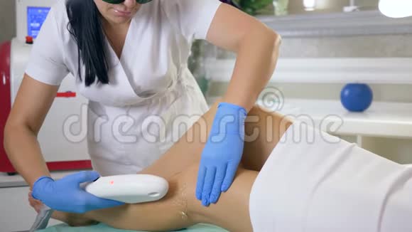 女性健康美容师使用激光设备在美容院的治疗室去除女士腿上的毛发视频的预览图