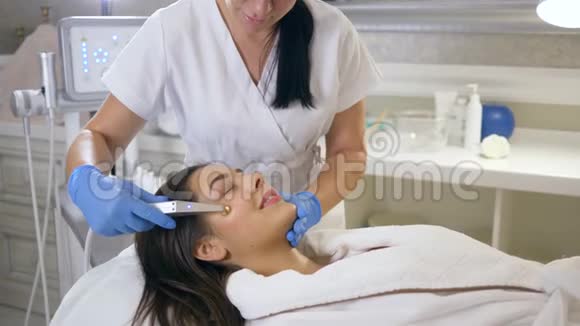 美容师在特殊帮助下在微笑女孩患者皮肤中进行纯氧供应视频的预览图