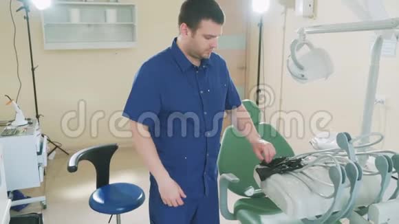 一位男性牙医在办公室里等待病人的慢镜头的肖像戴上医疗手套站着视频的预览图
