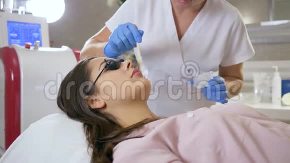身体护理美容师在女性客户的嘴唇上应用特殊凝胶进行激光脱毛视频的预览图