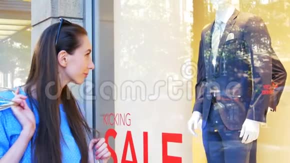 年轻漂亮的女人在商店橱窗里看男人的衣服视频的预览图