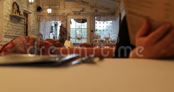 客人正在检查坐在咖啡馆桌子旁的菜单视频的预览图