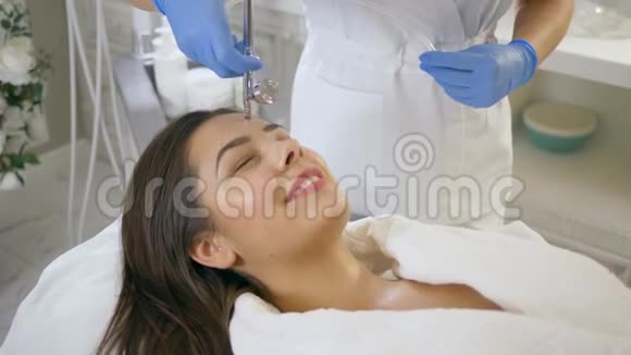 女性年轻化微笑的客户女孩在美容沙龙的程序滋养和恢复所有层次的皮肤视频的预览图