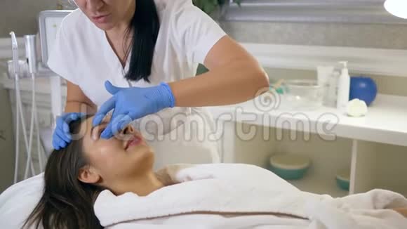 美容师在治疗过程中对女性患者面部应用具有年轻化效果的特殊凝胶护理视频的预览图
