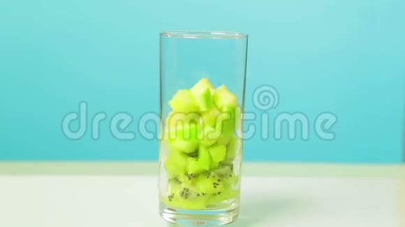 一只雌性手把草莓放进一个杯子里里面有几维和苹果片然后倒橙汁时光飞逝玻璃视频的预览图
