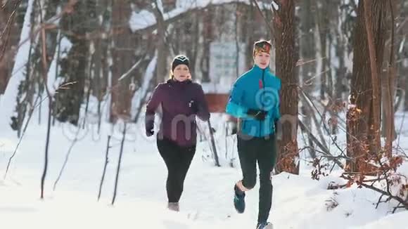 阳光明媚的冬林里一对年轻的运动夫妻在慢跑视频的预览图
