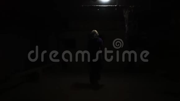 女人在黑暗阴暗的地下室走廊里移动视频的预览图