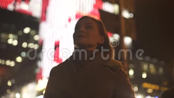 女游客站在灯火通明的街道上享受节日的灯光视频的预览图