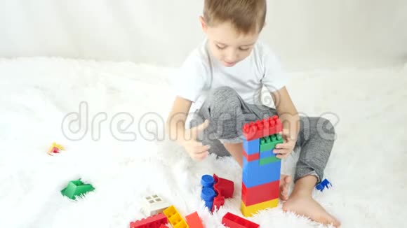 孩子在白色的背景上建造一座彩色积木塔儿童发展的概念视频的预览图
