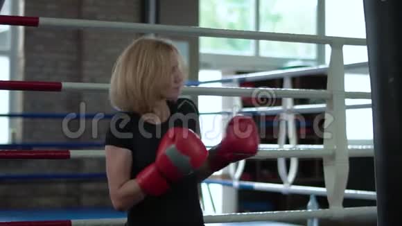 漂亮的运动女人在体育馆里用拳击袋拳击视频的预览图