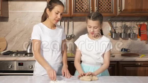 十几岁的女孩在家里的厨房里和她妈妈揉面视频的预览图