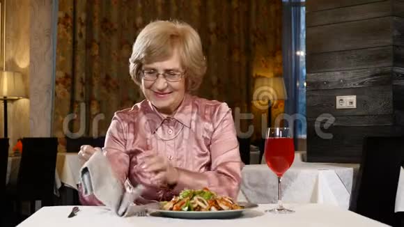 退休妇女坐在餐馆里桌上放着蔬菜沙拉和一杯新鲜水果饮料她70多岁的高级模特视频的预览图