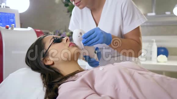 脱毛美容大师在水疗沙龙用激光对女性患者面部进行脱毛视频的预览图