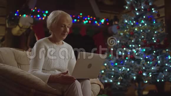 老太太用笔记本电脑在圣诞树上视频聊天视频的预览图