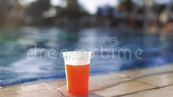 女人游泳到游泳池的边缘取新鲜的果汁喝它然后游泳离开阳光明媚的一天在游泳池里视频的预览图