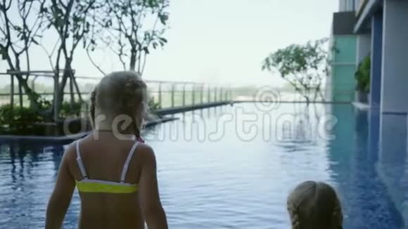 两个小女孩姐妹坐在全景池附近后景慢动作视频的预览图