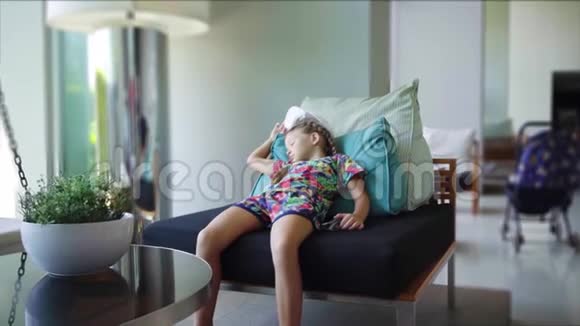 小女孩躺在全景窗附近的扶手椅上无聊动作缓慢视频的预览图