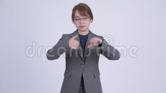 年轻迷茫的亚洲女商人在竖起大拇指和竖起大拇指之间做出选择视频的预览图