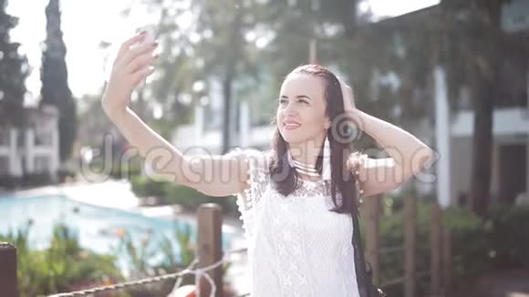 阳光下美丽的女孩在智能手机上自拍视频的预览图
