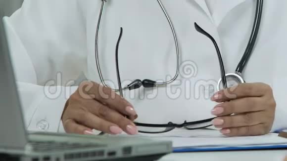 女治疗师手拿眼镜医生在笔记本电脑上看电子邮件视频的预览图