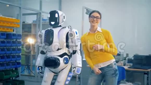 年轻女子正在拍打一个像人类一样的机器人因为它玩得很开心视频的预览图