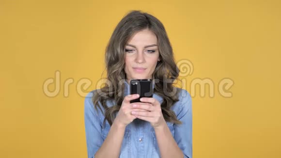 黄色背景下的少女智能手机视频的预览图