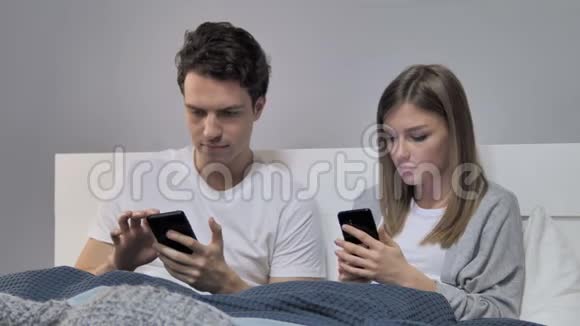 带智能手机的情侣在床上拍照视频的预览图