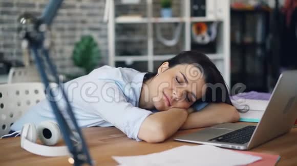 睡在书桌上在室内工作时放松的年轻女子的肖像视频的预览图