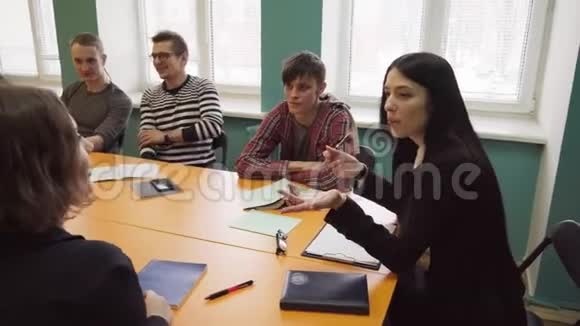 老师坐在桌旁和大学的学生交谈视频的预览图