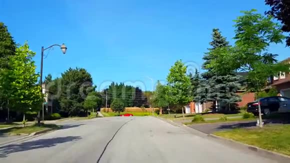在夏季驾驶接近住宅城市道路上的停车标志上面有树木查看POV的驱动点视频的预览图