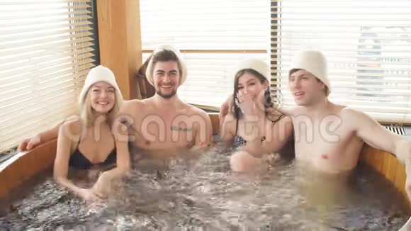 两对情侣在现代浴室享受带温水的热水木制按摩浴缸视频的预览图