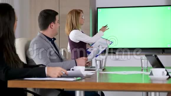 在绿色大屏幕电视前会议室的女商人视频的预览图