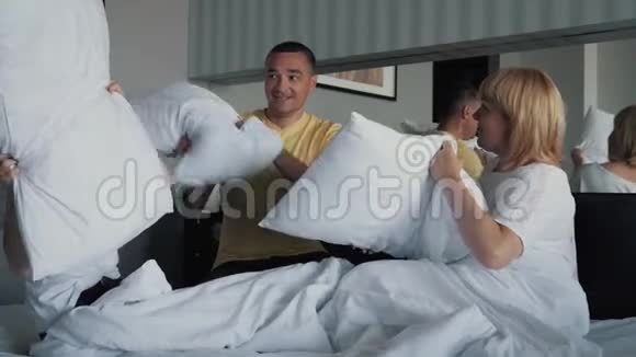一个幸福微笑的家庭在床上枕头在床上玩白色床单幸福家庭的概念视频的预览图