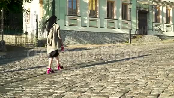 穿着时髦鞋子穿着粉色包包的迷人女人在城市的石路上散步视频的预览图